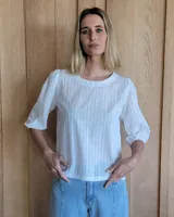 Remera blanca de algodón con mangas 3/4 abullonadas y cuello redondo. Presenta costuras a contratono en ruedo y cuello.