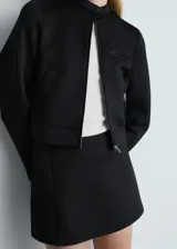 Minifalda negra de poliéster y elastano, con tiro medio, corte recto y cierre lateral con cremallera.