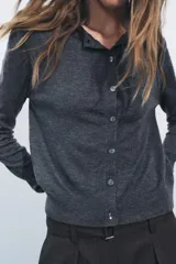 Chaqueta de punto fino color gris oscuro confeccionada con lana. Tiene cuello redondo, manga larga y cierre frontal con botones.