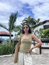 Musculosa verde oliva de morley, translúcida y elástica, con cuello redondo y detalles de costuras expuestas y pequeños dijes metálicos.