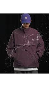 Chaqueta tipo anorak impermeable de color negro, con cuello alto y cierre parcial frontal. Presenta un pequeño logo en el pecho y ajuste regulable en la cintura para un calce más holgado o ceñido.