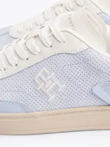 Zapatillas Tommy Hilfiger de cuero sintético color celeste con detalles en blanco y suela color crema. Presentan el logo de la marca bordado en el lateral y detalles distintivos en el talón.