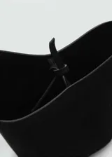 Bolso tipo bucket pequeño, color negro, con asa corta integrada y cierre de lazo ajustable.