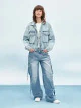 Campera de jean celeste con efecto lavado, corte cropped, cuello clásico, cierre frontal con botones metálicos, cuatro bolsillos frontales con solapa y puños abotonados.
