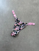 Colaless estampada con flores y hojas en tonos rosa, verde y marrón, con tiras regulables de lycra rosa.