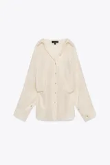 Camisa color crema de manga larga con cuello solapa y cierre frontal con botones.