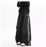 Pantalón deportivo negro de corte muy ancho (baggy) con cierre completo impermeable en los laterales. Presenta tres franjas blancas verticales en el lateral exterior de cada pierna. Posee reguladores en tobillos y cintura.