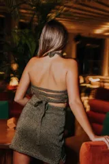 Vestido corto de punto con lurex color violeta, con cuello halter cruzado y aberturas en la cintura.