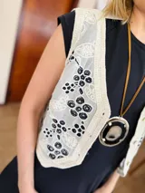 Chaleco color crema con bordados florales en negro y ribete de crochet.