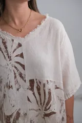 Blusa beige con estampado de hojas marrones, cuello en V y corte holgado.