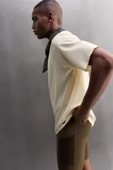 Camiseta deportiva marrón con estructura perforada, cuello redondo, manga corta y logo estampado.