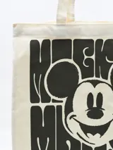 Bolso tipo tote bag de lona color crema con asas largas y estampado de Mickey Mouse en negro.