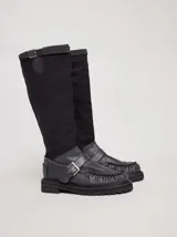 Bota de caña alta confeccionada en lona en la parte de la caña y en cuero el mocasín. Ajuste con hebilla cruzada y plataforma de 4cm de altura.