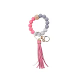 Llavero con pulsera de cuentas de silicona en tonos rosa y gris, con flecos de simil cuero rosa y gancho metálico dorado.