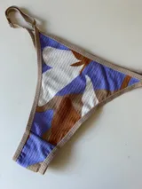 Bombacha tipo tanga con estampado abstracto en tonos lila, blanco y marrón.