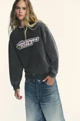 Sudadera gris con efecto lavado, cuello redondo, manga larga y rib en puños y bajo. Estampado frontal con el logo de Las Super Nenas.