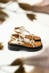 Sandalias con plataforma color marrón, con tiras de cuero color blanco y marrón con hebillas metálicas.