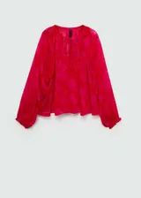 Blusa roja con estampado floral, de tejido fluido semitransparente y manga larga con puños elásticos. Tiene cuello redondo con cierre de lazo.