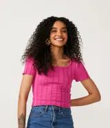Blusa de punto color fucsia con cuello redondo y mangas cortas. Tiene una malla texturizada con material responsable en la composición.