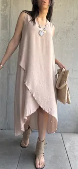 Vestido largo color beige, sin mangas, con escote redondo y corte irregular con volados.