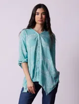 Blusa celeste con estampado de cachemir en blanco, cuello a la base, escote en V y abertura central con botones. Manga 3/4 regulable con presilla y botón, y terminación de ruedo asimétrico.