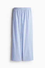 Pantalón de pijama celeste con rayas verticales blancas, de algodón suave, corte relajado, tiro bajo, cintura elástica, cierre decorativo con botones, piernas rectas y bolsillos laterales.