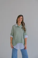 Sweater verde con cuello alto, mangas 3/4 y bajo asimétrico. Incluye una camisa blanca de mangas largas y una bufanda de encaje verde.