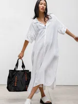 Vestido camisero blanco de lino con botones frontales, mangas cortas y corte midi con aberturas laterales.