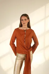 Blusa color ladrillo con escote redondo, manga larga y nudo en la cintura.