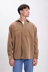 Sobrecamisa de pana color tostado, de corte recto, con cuello camisero, cierre frontal con botones, dos bolsillos de parche en el pecho y mangas largas con puños abotonados.