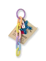 Llavero con cadena de eslabones de plástico en colores pastel, dije de perro globo azul metálico y etiqueta de tela con texto.