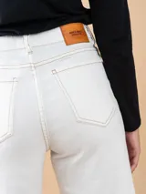 Jean ancho color crudo con corte recto, tiro alto y ruedo deshilachado.