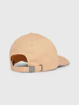 Gorra de béisbol color beige con visera ribeteada con cinta tricolor (rojo, blanco, azul). Presenta el logo de Tommy Hilfiger bordado en el frente.