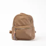 Mochila pequeña color beige con múltiples cierres plateados y colgante decorativo de cordones trenzados.