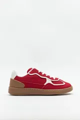 Zapatillas urbanas rojas de gamuza con recortes en símil cuero blanco y marrón, y suela de goma color caramelo.
