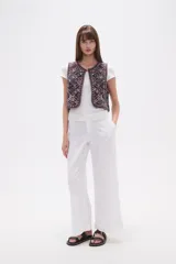 Chaleco sin mangas, sin abroches, con escote redondo. Confeccionado en tejido oscuro con bordados geométricos y florales en tonos rojos, blancos, azules y mostaza, con apliques de cuentas.