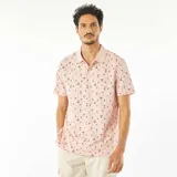 Remera polo de piqué de algodón color rosa con estampado de palmeras y tablas de surf en negro.