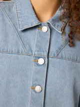 Camisa de denim celeste con cuello clásico, mangas cortas y cierre con botones.