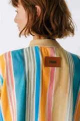 Camisa oversize con cuello mao, manga corta con terminación en puño, botones de metal a la vista y tajos laterales.