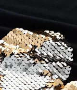 Remera negra de algodón con cuello redondo y manga corta. Presenta un estampado frontal de un corazón dorado de lentejuelas reversibles y texto blanco.