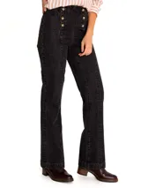 Pantalón de jean negro con corte boot leg, tiro alto y cierre frontal con botones dorados.