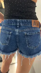 Short de jean azul con tiro bajo y ruedo desflecado.