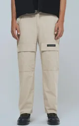 Pantalón cargo beige de corte recto con bolsillos laterales y etiqueta con logo en la pierna.