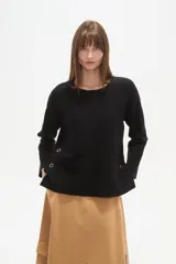 Sweater blanco liso, de corte holgado, con cuello a la base y broches decorativos en los laterales.