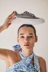 Zapatillas grises con cordones y suela blanca.