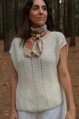 Chaleco color crudo tejido a mano en hilado 100% baby alpaca, con cuello tipo bote, hombros anchos, puntos calados en frente y espalda, y tajos laterales en el bajo.