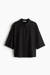 Camisa negra de lino y viscosa, corte holgado, mangas al codo, cuello clásico y cierre con botones.