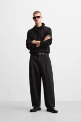 Polo de manga larga color negro, de punto tejido en hilatura de algodón, corte relaxed fit, con cuello solapa y cierre frontal de botonadura.