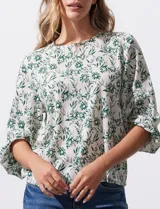 Blusa de gasa estampada con flores verdes sobre fondo blanco, de la marca Sioni. Tiene mangas cortas amplias con abertura y botón.