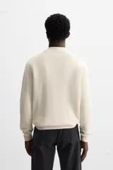 Polo marrón de punto con hilatura de algodón, corte relaxed fit, cuello solapa con cierre frontal de botonadura, manga larga y acabados en rib.